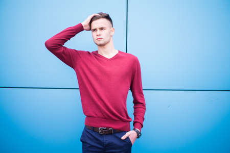 young guy in a red sweater on a blue backgroundの写真素材