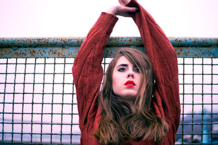 beautiful and fashionable girl standing with a bare shoulder in the winter near the fence of the rabitの写真素材