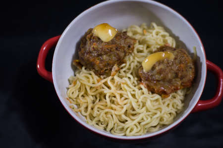 Meatballs with noodles in a red tureen on a black backgroundの写真素材