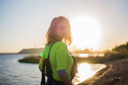 A girl wearing glasses on the beach in the evening at sunsetの写真素材