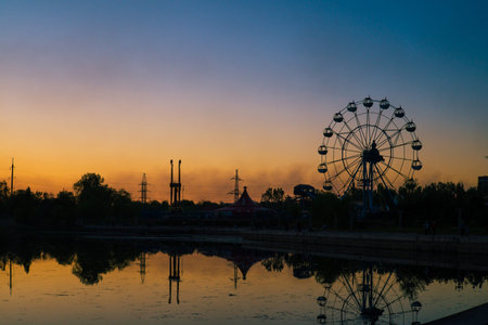 Silhouette of a Ferris wheel with reflection in the river at sunset
