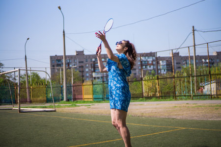 Girl playing a game of badminton on a football field on a sunny summer day