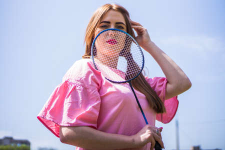 A girl on a football field on a sunny and bright day goes in for sports and plays a game of badmintonの写真素材