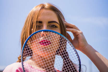A girl on a football field on a sunny and bright day goes in for sports and plays a game of badmintonの写真素材