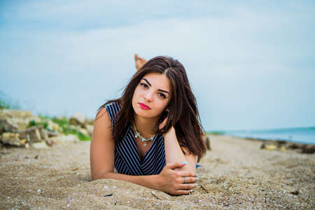 The brunette girl lies on the sand by the seaの写真素材