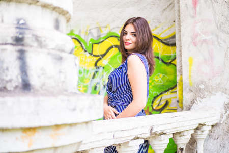 A white-haired brunette girl sits on the balcony of an old abandoned painted sceneの写真素材