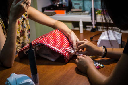 The master of nail extensions and coating with gel varnish makes correction to his client in the beauty salonの写真素材