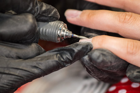 The master of nail extensions and coating with gel varnish makes correction to his client in the beauty salonの写真素材