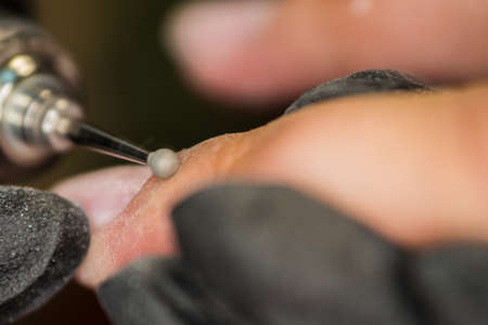 The master of nail extensions and coating with gel varnish makes correction to his client in the beauty salonの写真素材