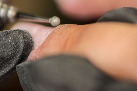 The master of nail extensions and coating with gel varnish makes correction to his client in the beauty salonの写真素材