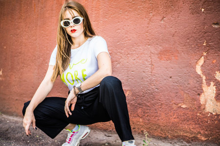 Fashionable girl in broad trousers and a white T-shirt and a denim jacket, and fashionable glasses...