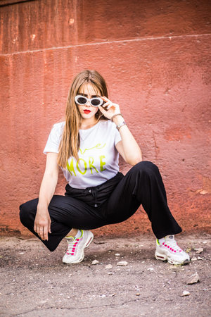 Fashionable girl in broad trousers and a white T-shirt and a denim jacket, and fashionable glasses...