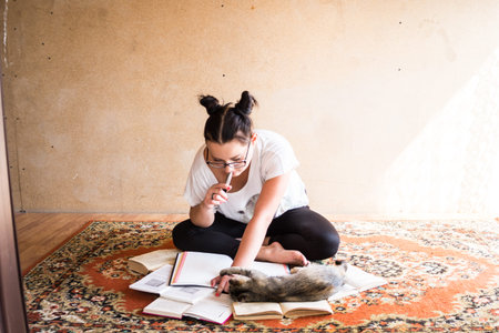 Young girl student with fashion hairstyle horns on her head, doing homework on the floor at home