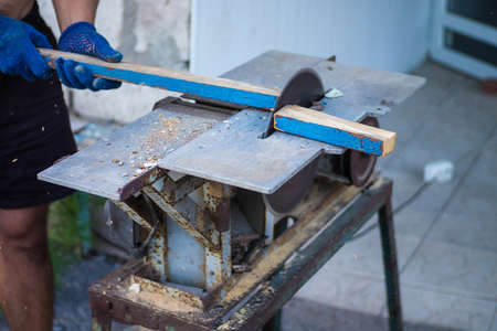 A man is sawing wood on a sawmill, prepared for the winter, makes logsの写真素材