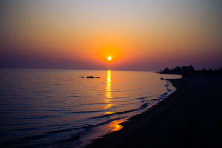 Sunset of fiery sol against the sea with wavesの写真素材