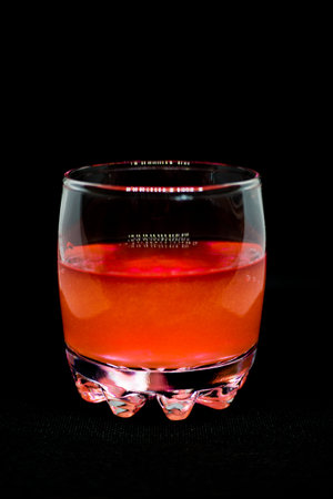 Glitter orange drink in a glass transparent glass isolated on black background close-up