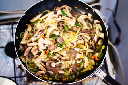 Cook at home. Homemade dish in a pan, stewed hearts with vegetables and mushrooms.の写真素材