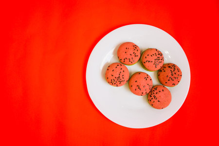 Multi-colored green and pink, bright cookies with two halves dressed with filling and sprinkled with...