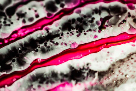 Black and pink refill ink spilled onto the white sink and the ink mixed into abstract blobs and patterns.の写真素材