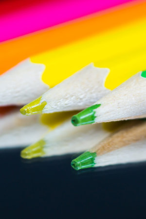 Colored and sharpened pencils lie on the mirror and are reflected in it.