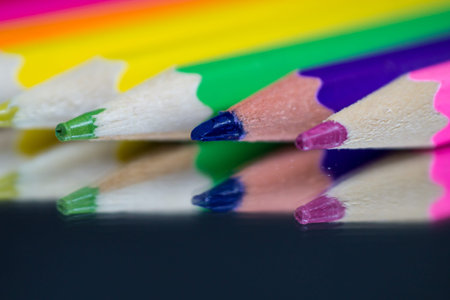 Colored and sharpened pencils lie on the mirror and are reflected in it.