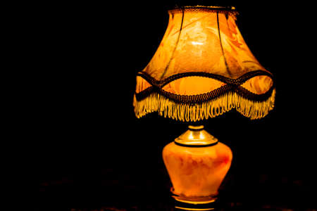 A room night lamp stands in a dark room on a carpet and illuminates the room.の写真素材