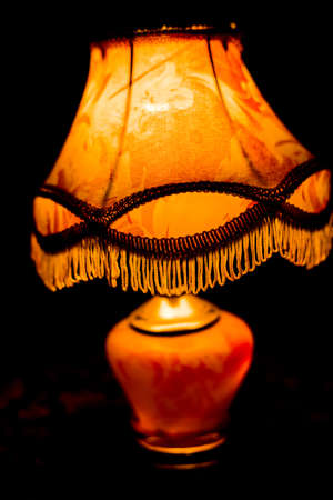A room night lamp stands in a dark room on a carpet and illuminates the room.の写真素材