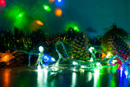 Toy balls on the Christmas tree and cones with multi-colored garlands close-up.の写真素材