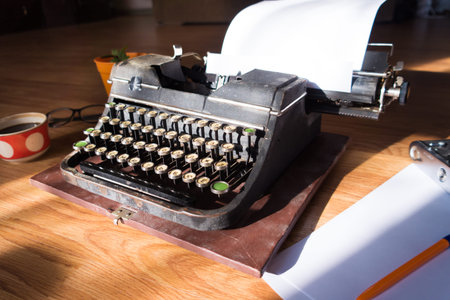 Old antique typewriter with inserted paper for writing articles and books on the desktop.