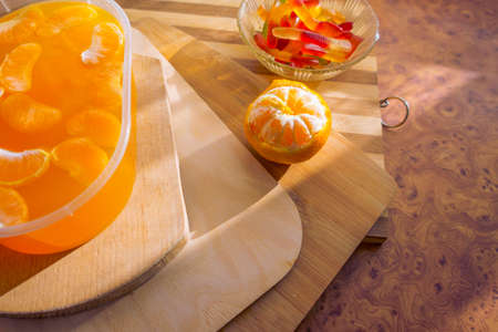 Orange jelly in a plastic container with tangerine slices on wooden planks.の写真素材