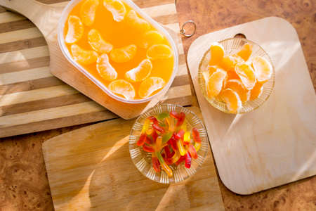 Orange jelly in a plastic container with tangerine slices on wooden planks.の写真素材