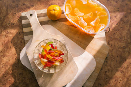 Orange jelly in a plastic container with tangerine slices on wooden planks.の写真素材
