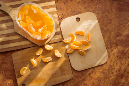 Orange jelly in a plastic container with tangerine slices on wooden planks.の写真素材