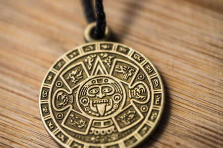Aztec calendar amulet on a wooden background close-up.の写真素材