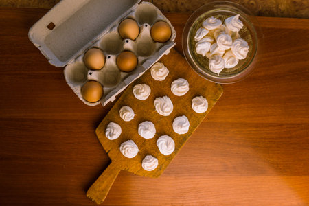 Delicious crispy homemade egg meringue, prepared with love on a wooden background, crunchy dessert...