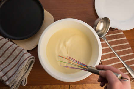 pancake week. Preparation of dough for baking delicious and ruddy pancakes from the ingredients eggs, flour, butter and milk. Maslenitsa traditional Russian festival meal.の写真素材