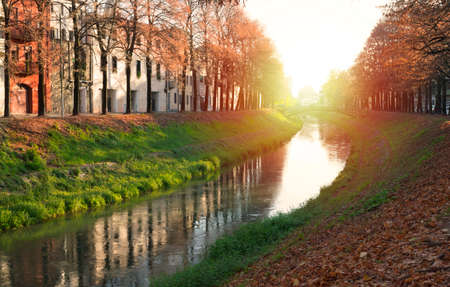 autumn red trees river bridge in the park during sunsetの写真素材