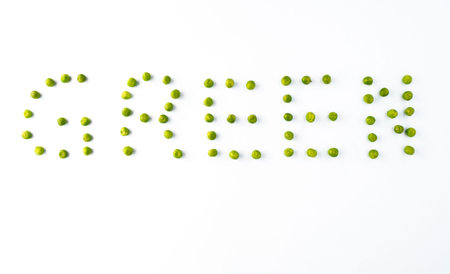 word GREEN made from green peas on white background isolated の写真素材