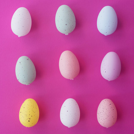 Pale pink, blue, yellow and green Easter eggs on pink background