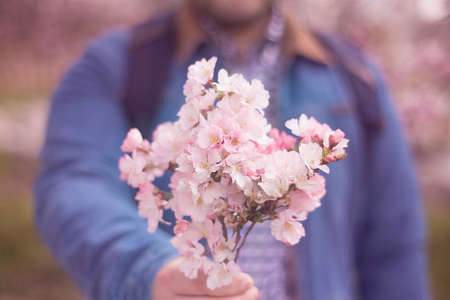 a young man giving boquet of pink flowers, spring, love and romantic concept. Horizontalの写真素材