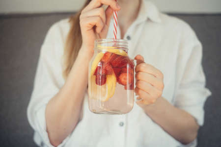 cropped shot of young woman drinking home made fresh summer drink from mason jar with strawの写真素材