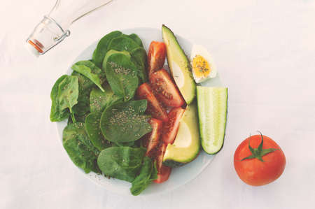 flat lay with arranged salad in bowl, spices and bottles of oil on white tablecloth. Healthy vegetarian foodの写真素材