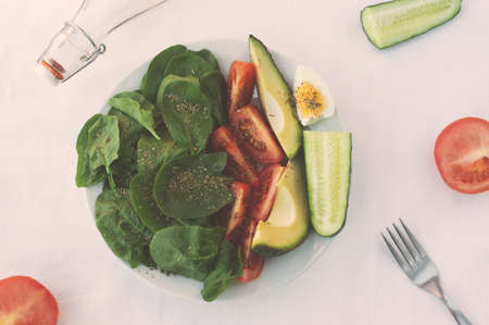 flat lay with arranged salad in bowl, spices and bottles of oil on white tablecloth. Healthy vegetarian foodの写真素材