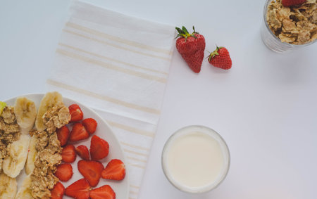 Flat-lay, tasty summer healthy vegetarian breakfast with fruits, milk and cereal on white backgroundの写真素材