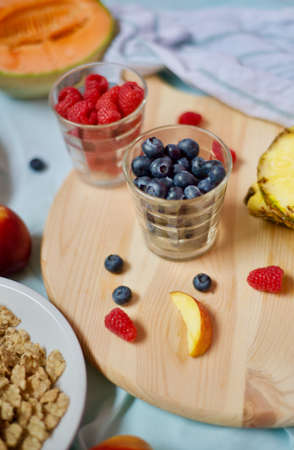 tasty healthy eating vegetarian vegan detox breakfast with fresh seasonal fruits and berries served on chopping board over pastel blue backgroundの写真素材