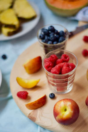 tasty healthy eating vegetarian vegan detox breakfast with fresh seasonal fruits and berries served on chopping board over pastel blue backgroundの写真素材