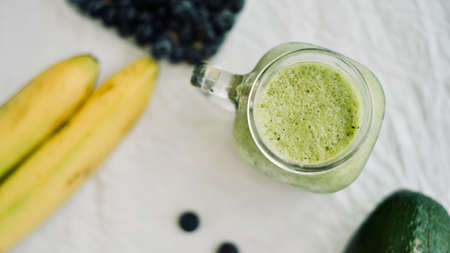 green avocado banana blueberries smoothie in a glass jar over white background, healthy eating,detox, summer dietの写真素材