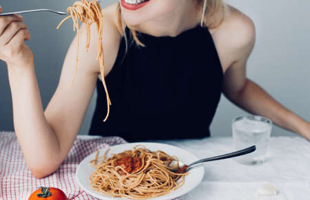 young attractive beautiful girl woman eating Italian food a plate of pasta with sugo, lifestyle. Italian food concept, , home made food, cooking at home,の写真素材