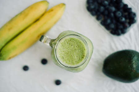 green avocado banana blueberries smoothie in a glass jar over white background, healthy eating,detox, summer dietの写真素材
