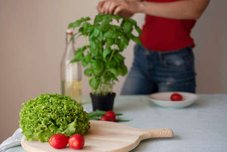 young woman wearing jeans cooking healthy vegetarian detox food. Ingredients and preparation for healthy Italian foodの写真素材